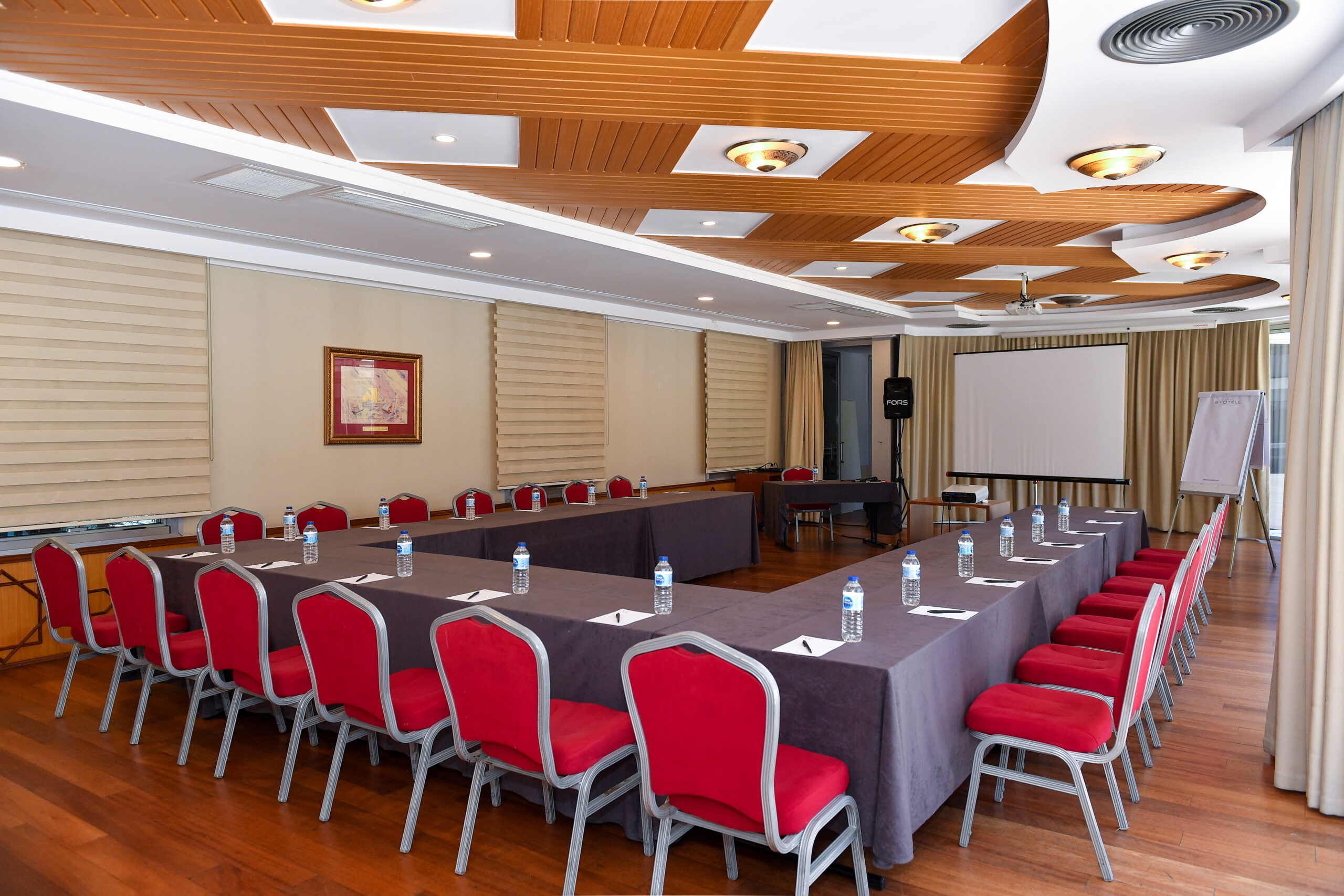 Olacak Event’in İstanbul’da geniş toplantı salonu, kırmızı sandalyeler ve uzun bir masa ile kurumsal etkinlikler için.”